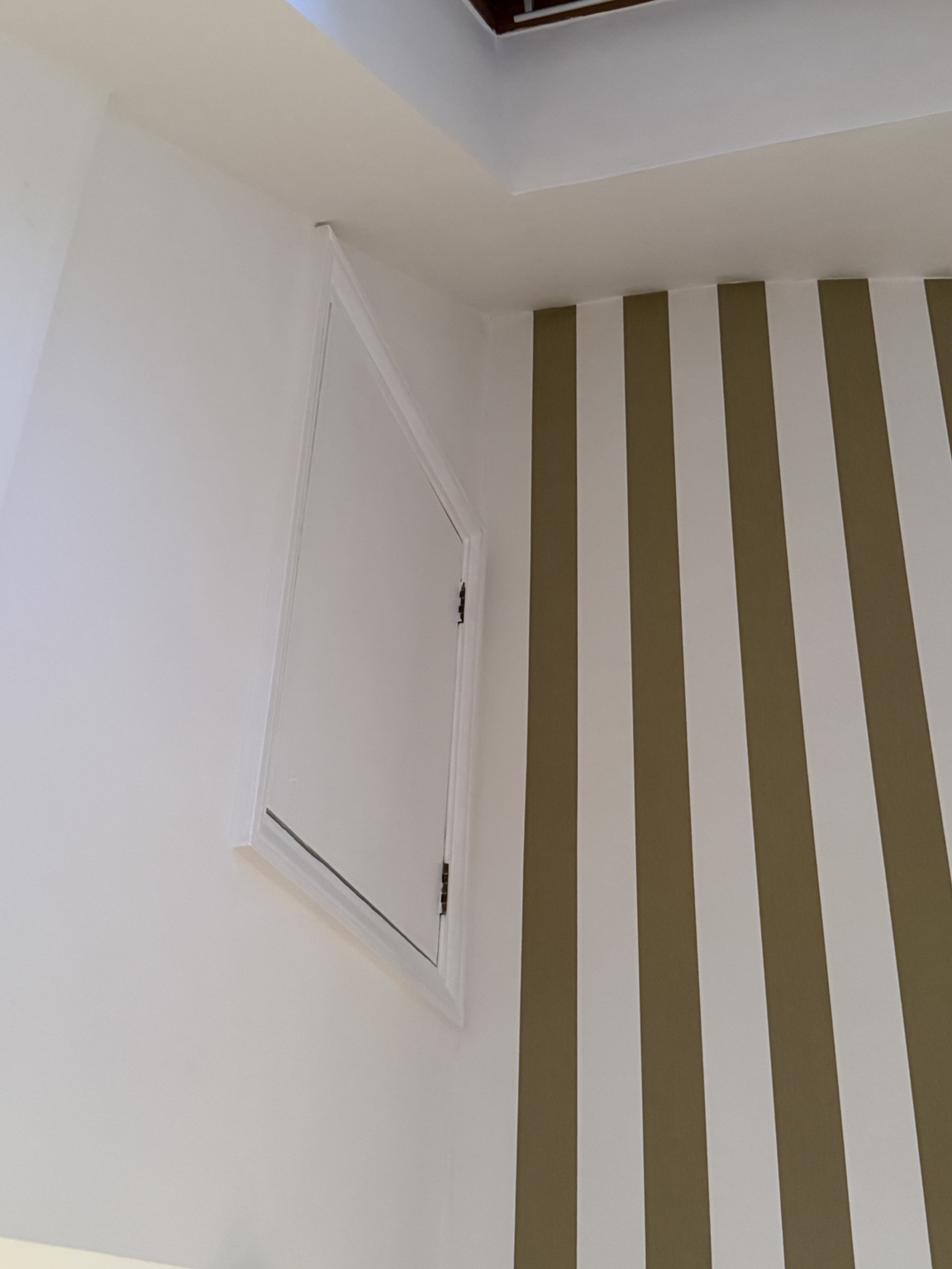 Decorated room with striped feature wall and loft access hatch